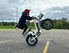 Man lifts the front wheel of the G-force RS ST electric bike on concrete, showing its strong power and stability.